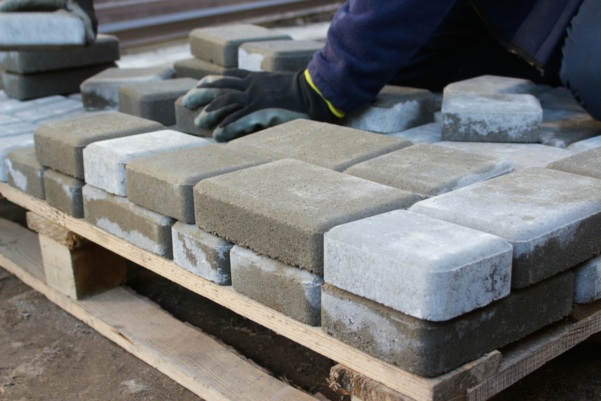 paver master. Man lays paving stones in layers. Garden brick pathway paving by professional worker.